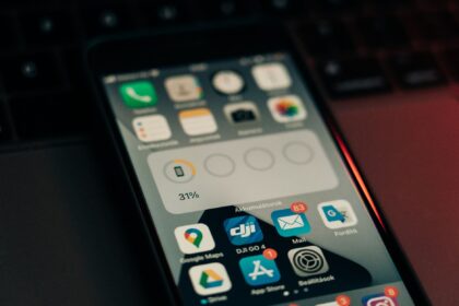 A smartphone with various apps on its screen placed on a keyboard, showing a 31% battery level.