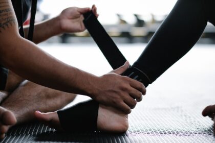 Close-up of an athlete's ankle being wrapped with an elastic bandage in a gym setting.