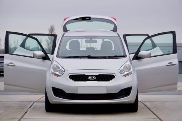 Front view of a silver Kia car with all doors open, parked on pavement.