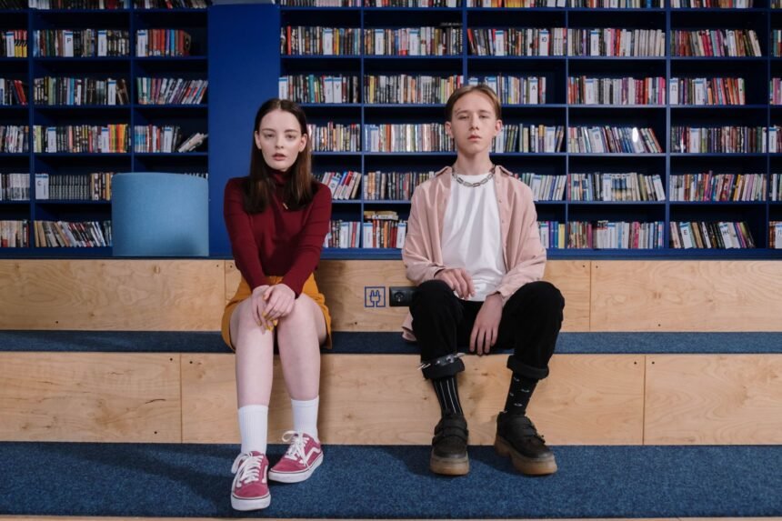 Two teenagers sitting on library steps, showcasing a modern casual fashion scene.