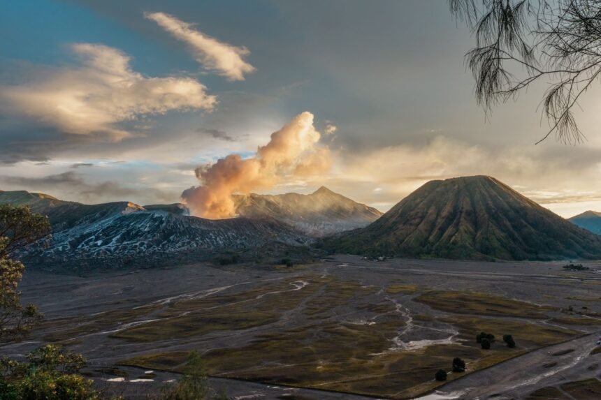 A breathtaking view of Mount Bromo in East Java, Indonesia, with erupting smoke at sunrise.