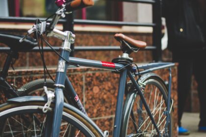 A close-up of a parked bicycle against a tiled wall in a city setting.