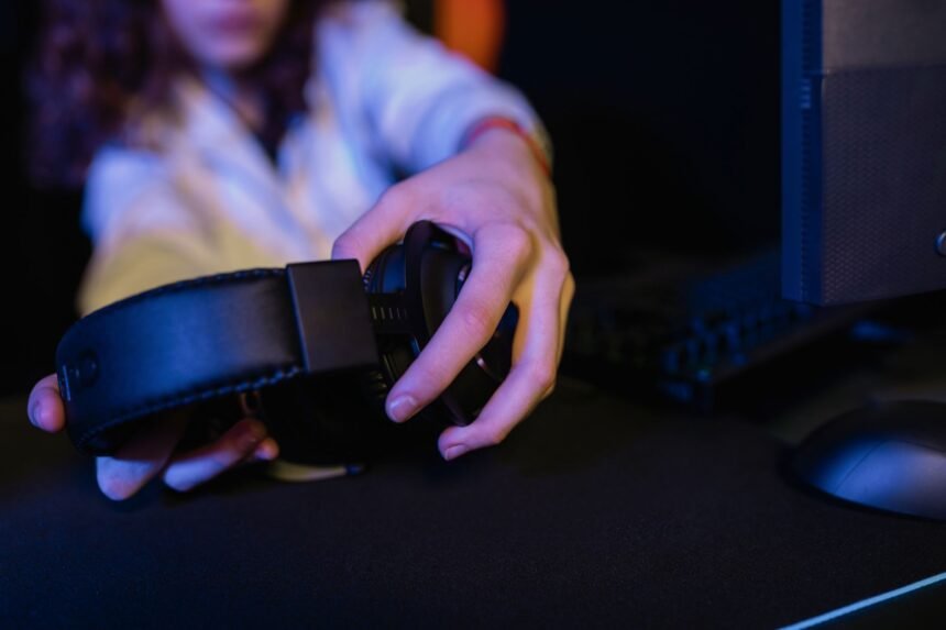 Close-up of a person holding a gaming headset in a computer setup.