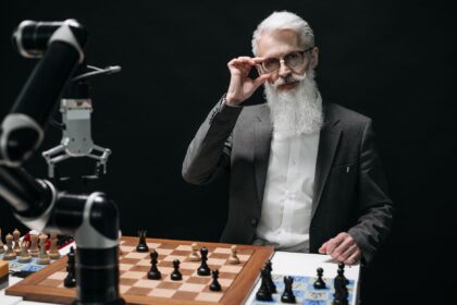 Senior man strategizing in a chess game against a robot, showcasing AI in leisure activities.