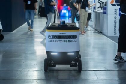 Autonomous delivery robot navigating indoors during a technology event.