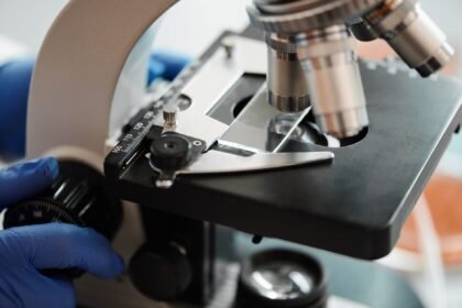 Detailed view of using a microscope with gloved hands in a lab setting.