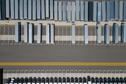 High-angle shot of trucks parked in an organized grid in an industrial parking lot.