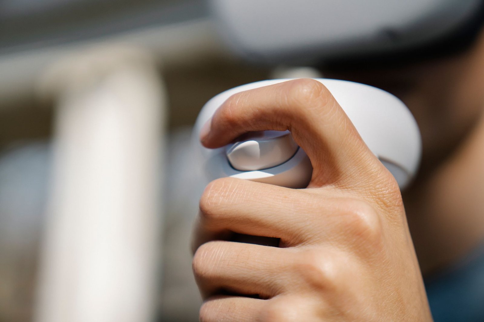 Closeup crop male in VR goggles using modern wireless controller near building on street in daylight