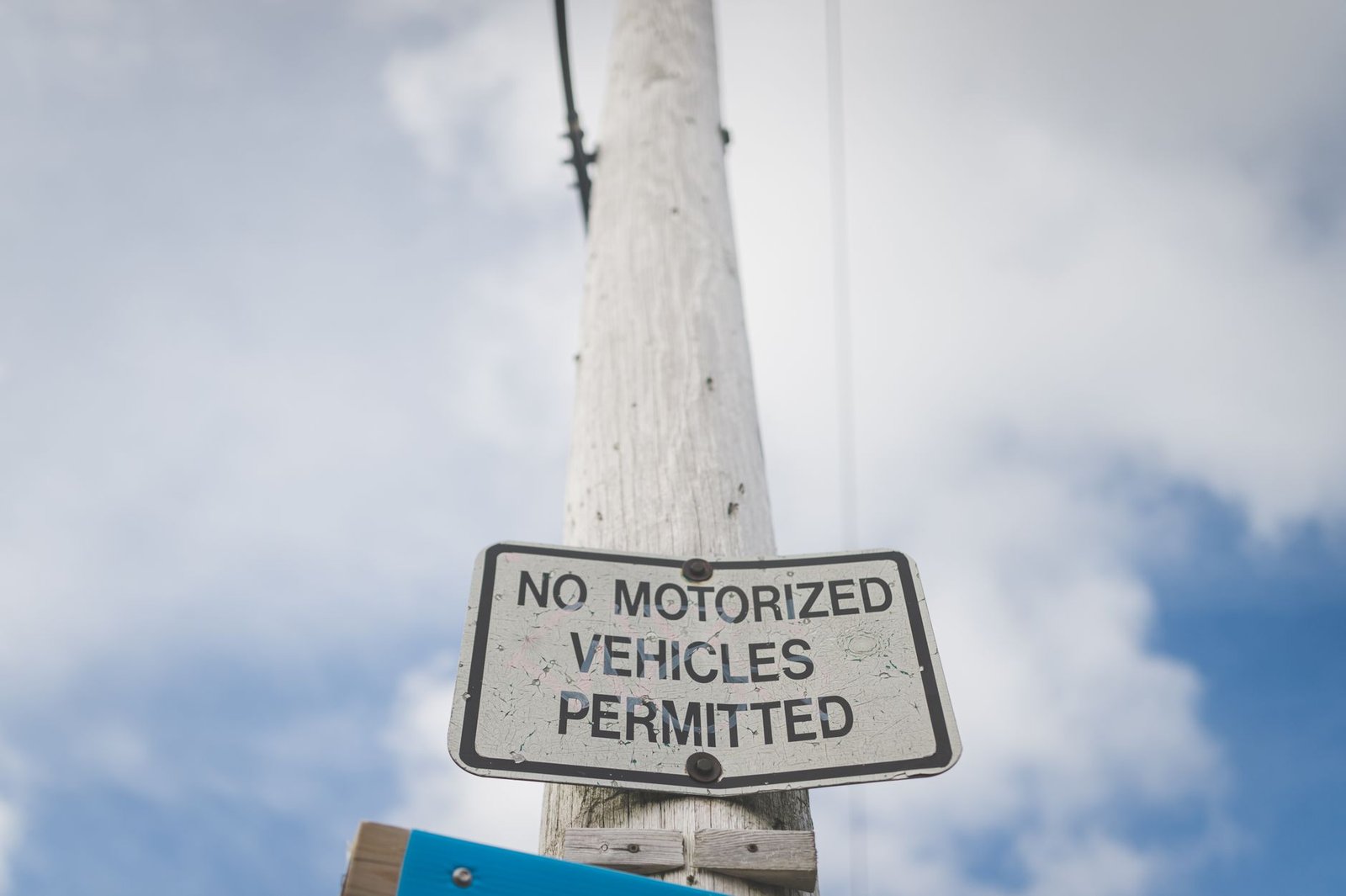 A street sign prohibiting motorized vehicles, mounted on a post against a blue sky.