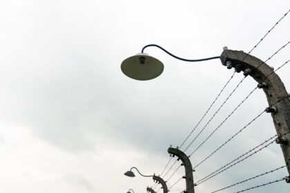 Low angle view of an overcast sky with barbed wire fence and lamps.