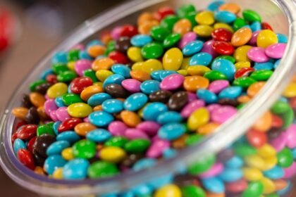 A glass bowl filled with colorful candy-coated chocolates, perfect for a festive party setting.