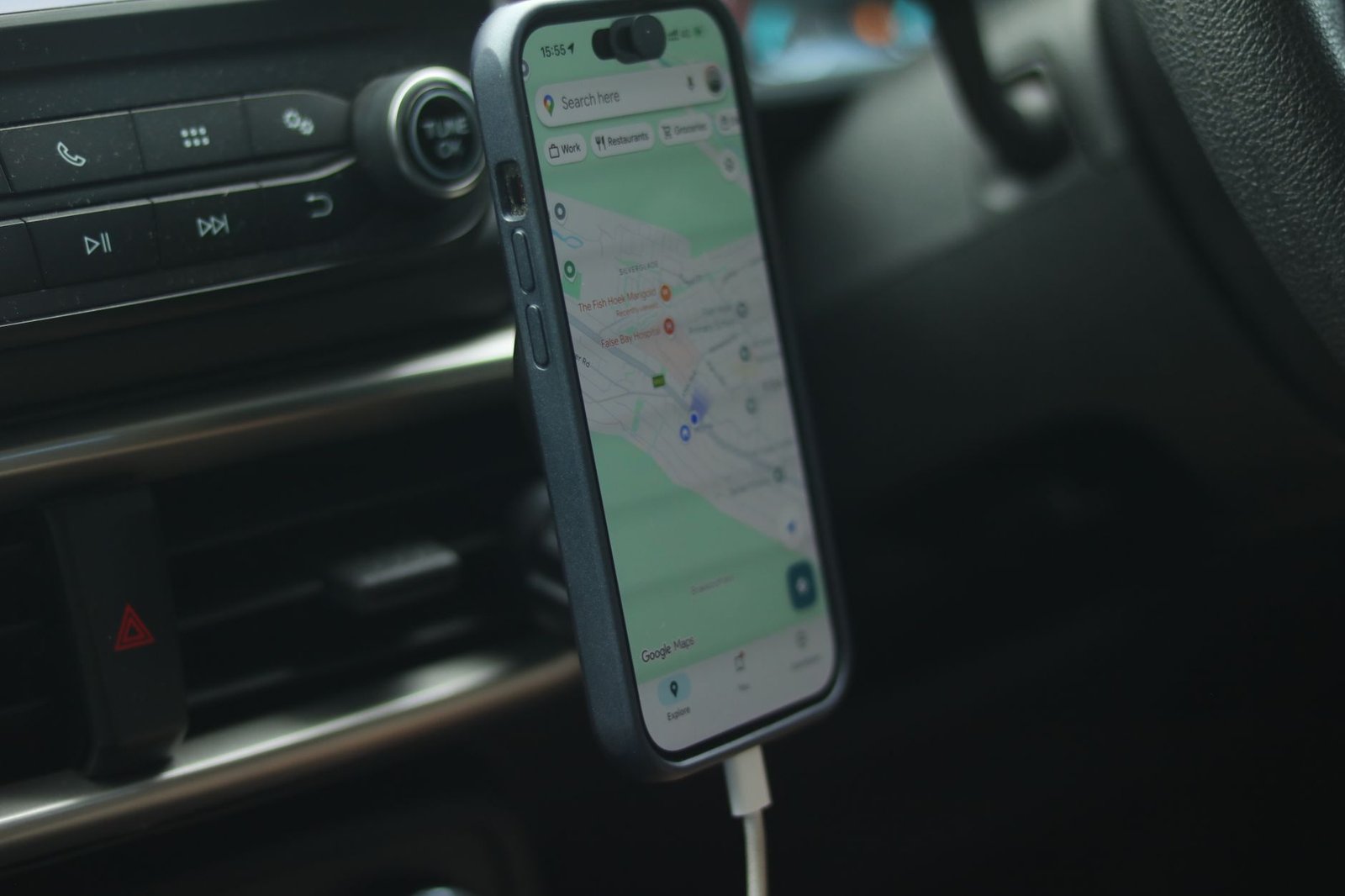 A smartphone with a map app displayed inside a car, showing modern navigation.