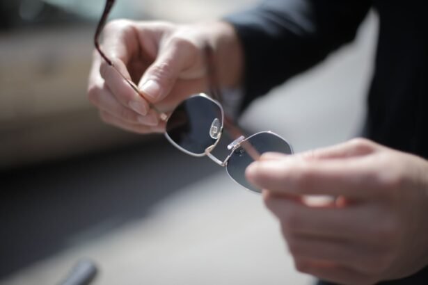 A detailed close-up of hands holding stylish sunglasses outdoors with a blurred background.