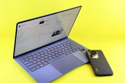 A sleek laptop and smartphone set against a vibrant yellow background, showcasing modern technology.