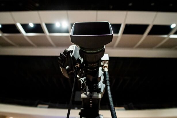 Low angle of professional video camera with lens on tripod placed under ceiling with lights in studio