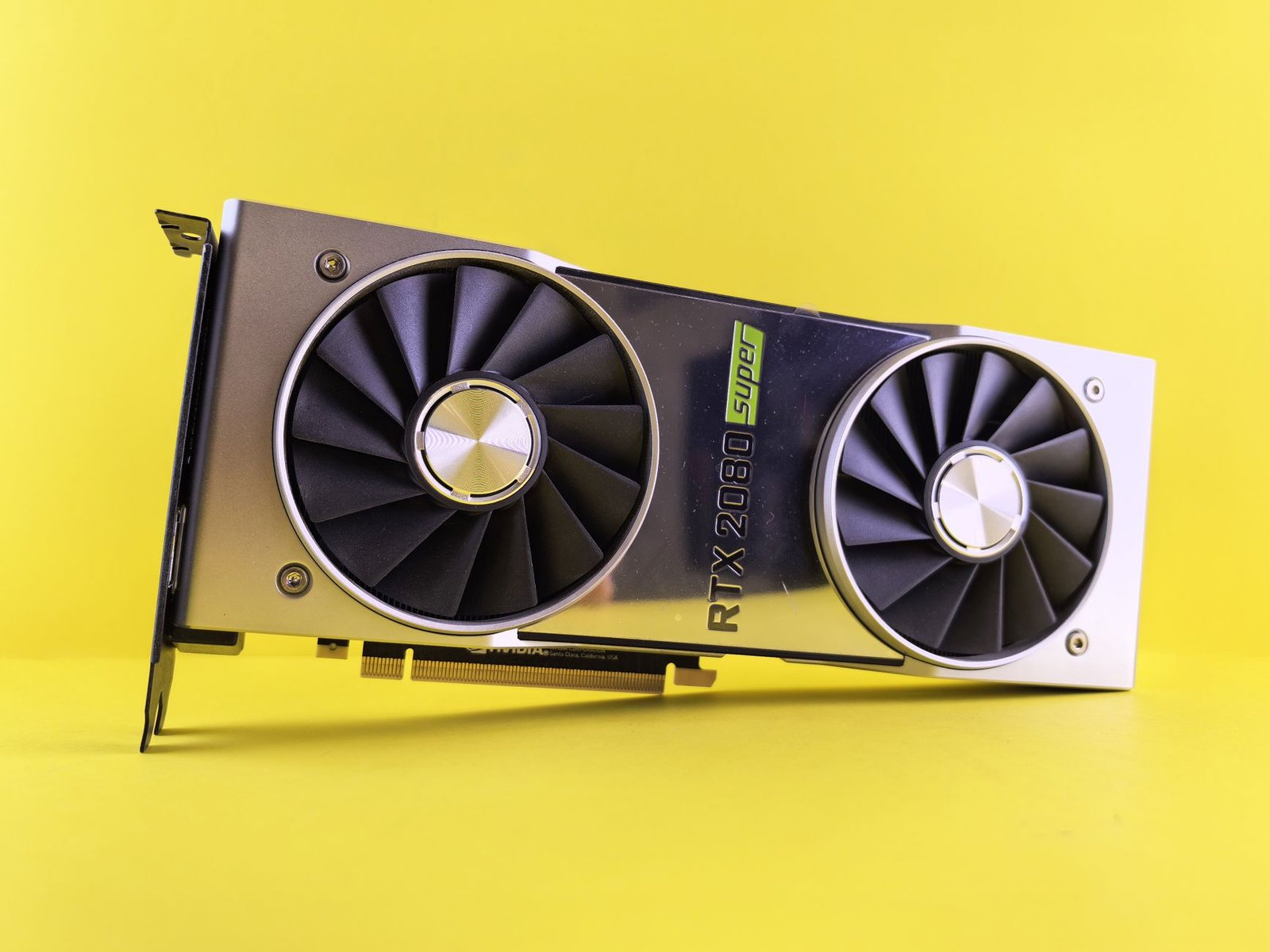Close-up of a RTX 2080 Super graphics card against a bright yellow backdrop, showcasing high-tech design.
