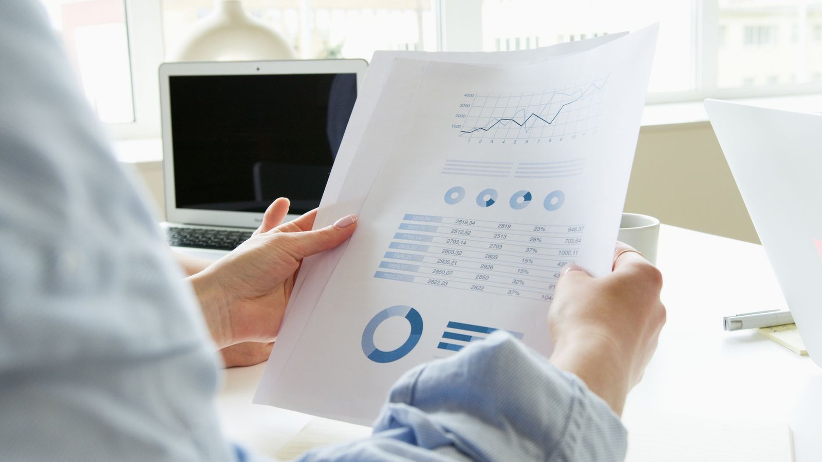 Close-up of a person analyzing business charts and graphs indoors.