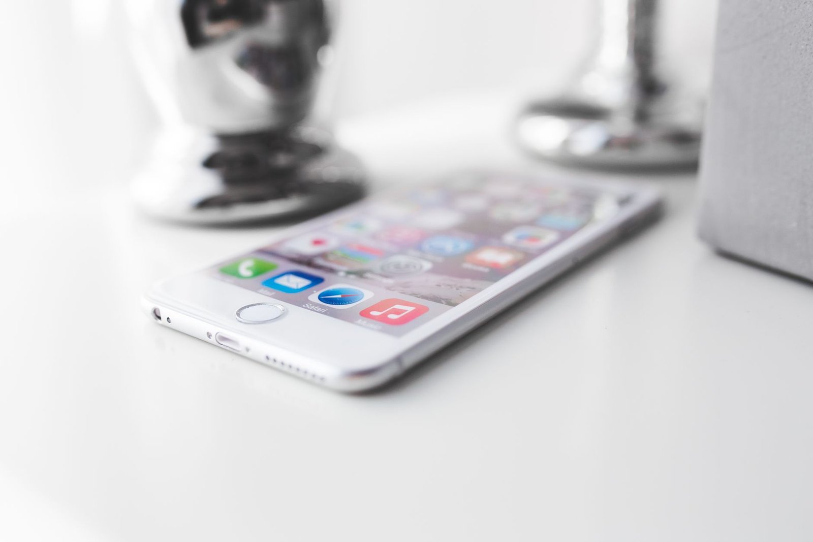 Close-up of a modern silver smartphone on a white surface with apps visible.