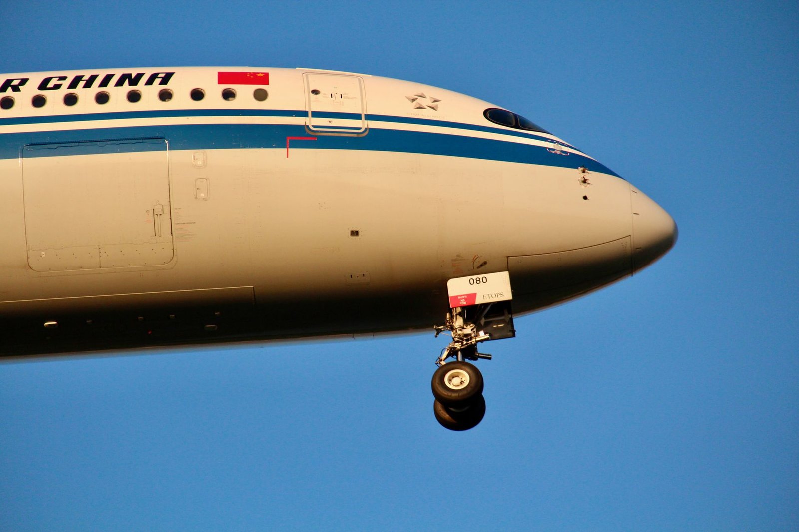 Close-up view of an Air China airplane in flight, showcasing its landing gear and fuselage.