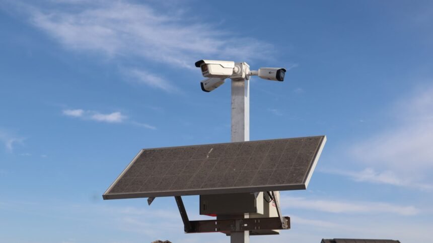 Surveillance camera powered by solar panel against a clear blue sky in Sacramento.