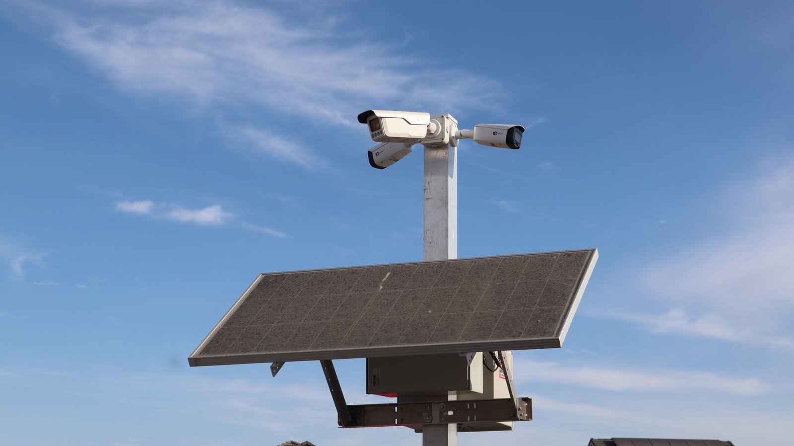 Surveillance camera powered by solar panel against a clear blue sky in Sacramento.