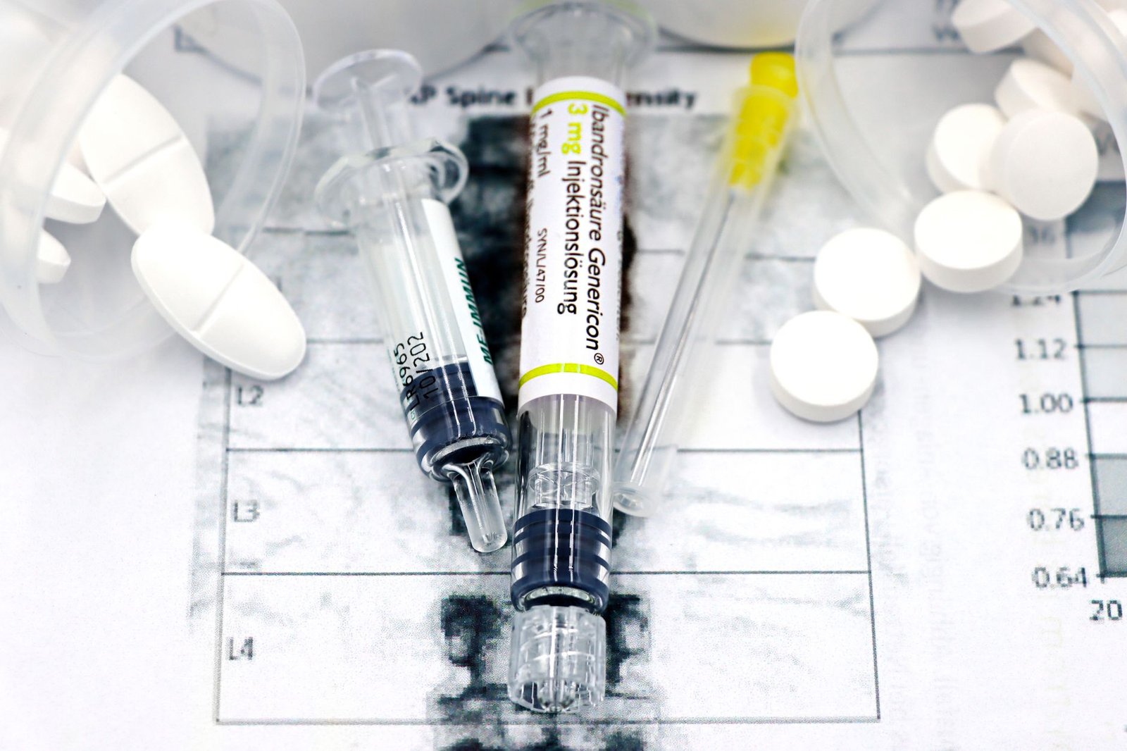 Close-up of syringes and pills on a bone density exam sheet, depicting osteoporosis treatment.