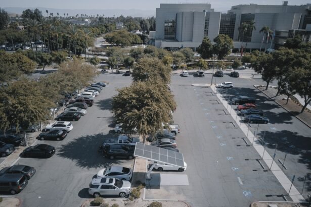 High-angle view of a parking lot with solar panels and parked vehicles, surrounded by greenery.
