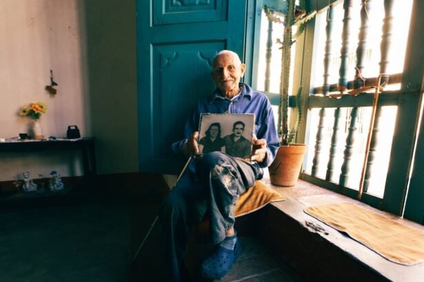 Senior man seated by window, reminiscing with a nostalgic photo.