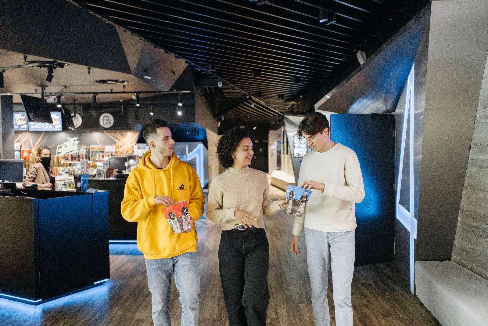 Three friends walking in a movie theater with popcorn, ready for a cinematic experience.