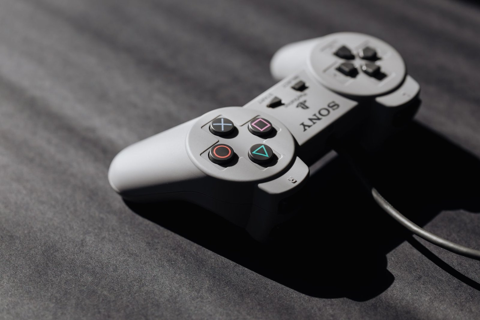 Retro Sony game controller with classic buttons on a textured dark surface, showcasing vintage electronics.