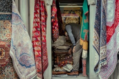 Vibrant market stall showcasing a variety of colorful traditional rugs and carpets, capturing local commerce.