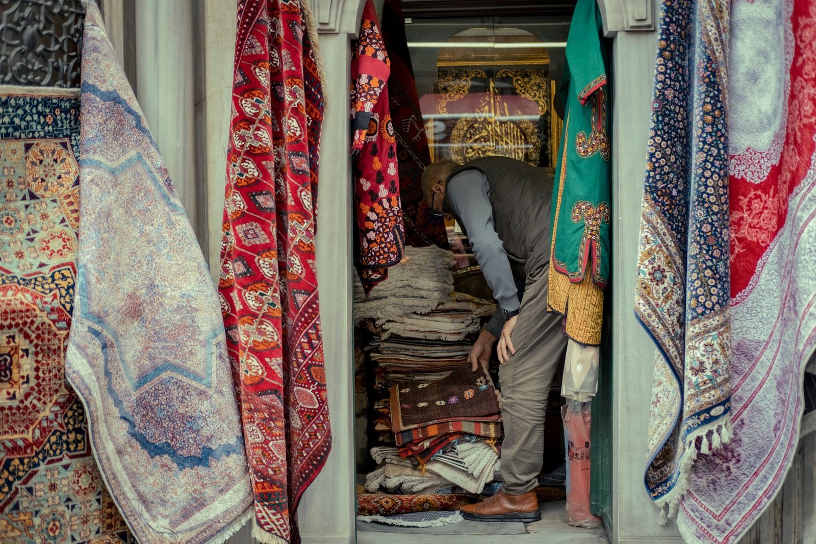 Vibrant market stall showcasing a variety of colorful traditional rugs and carpets, capturing local commerce.