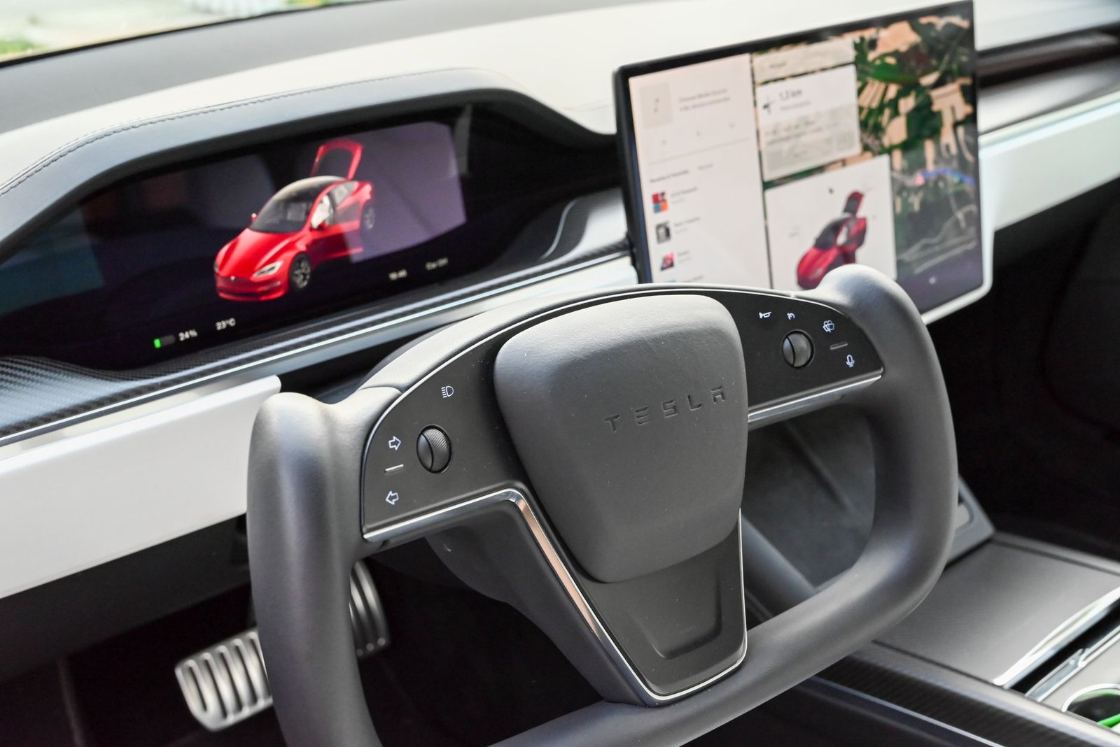 Modern Tesla car interior featuring a steering yoke and digital displays showcasing features.